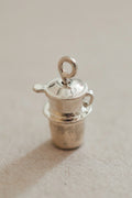 A small silver-colored metal coffee cup with a fin, possibly a decorative item or a collectible.