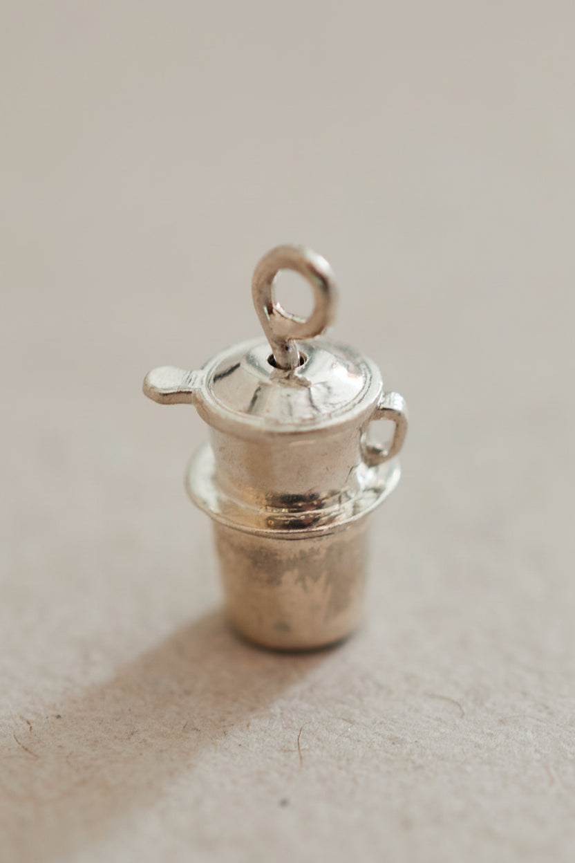 A small silver-colored metal coffee cup with a fin, possibly a decorative item or a collectible.